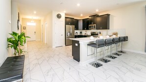 Una cocina moderna con armarios oscuros, una isla central con taburetes de bar y un reloj en la pared.