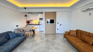 A modern living room with a grey sofa, a brown sofa, and a dining area with a table and chairs. - Gurol Hotel & Apart (Fethiye)
