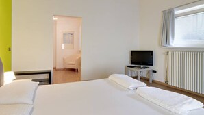 Une chambre d’hôtel avec un grand lit, un téléviseur posé sur une petite table et un radiateur.