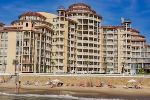 A large hotel with multiple balconies, a beach in front, and a clear blue sky. - Menada Andalusia Apartments (Elenite)