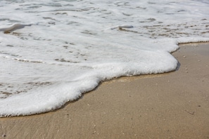 A close-up of a sandy beach with foamy waves. - Menada Andalusia Apartments (Elenite)