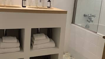 Un baño con tocador de madera, cabina de ducha de vidrio y baldosas de piso estampadas.