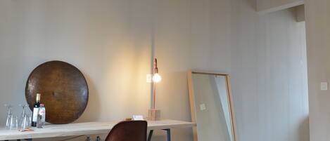 A room with a wooden ceiling, a desk with a chair, a large mirror, and a patterned rug.