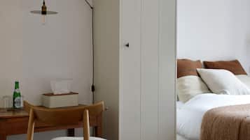 Une chambre à coucher avec un lit, une chaise en bois, un bureau avec une bouteille et une armoire.