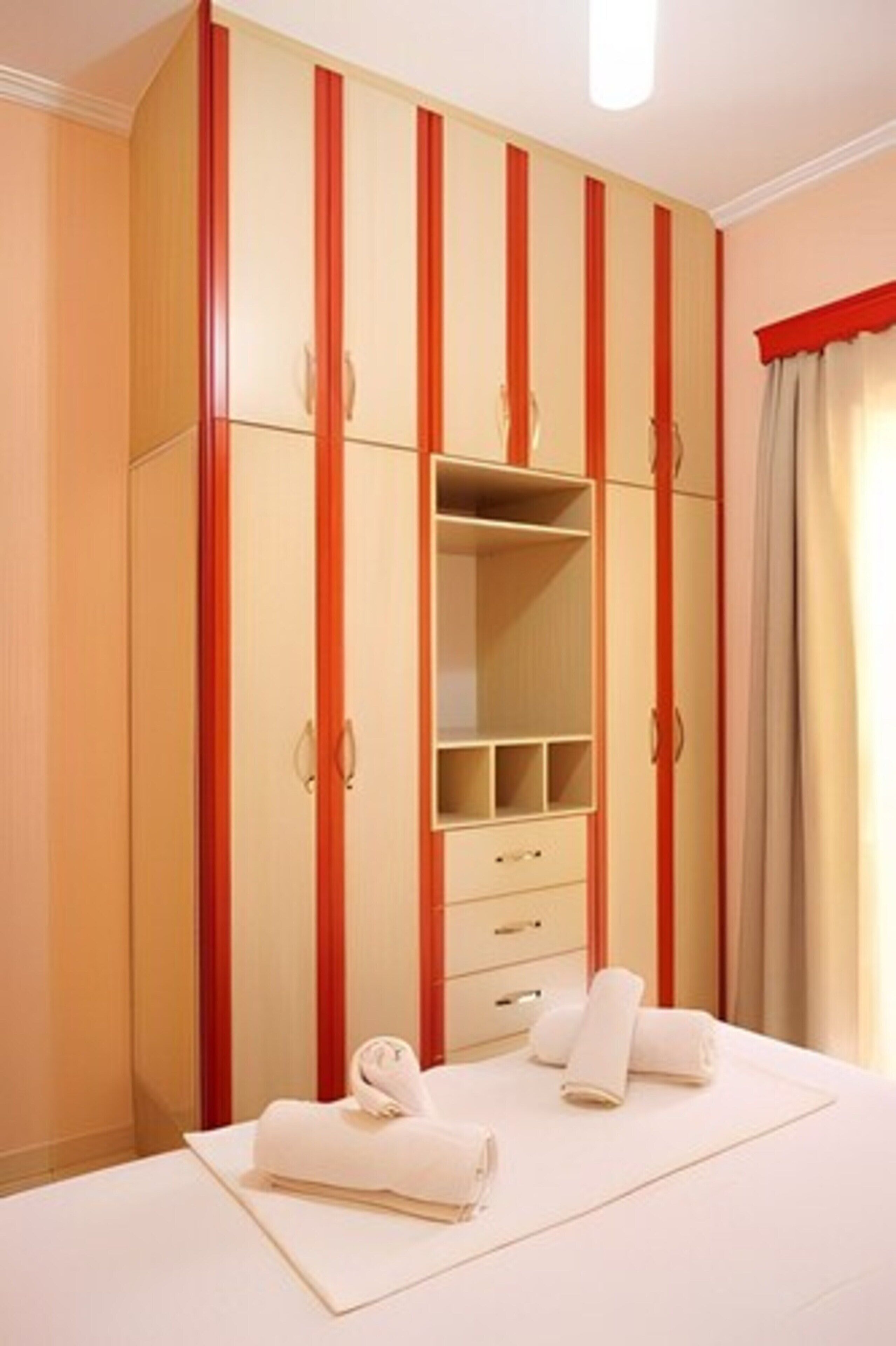 A bedroom with a large wardrobe, a bed, and a window with curtains.
