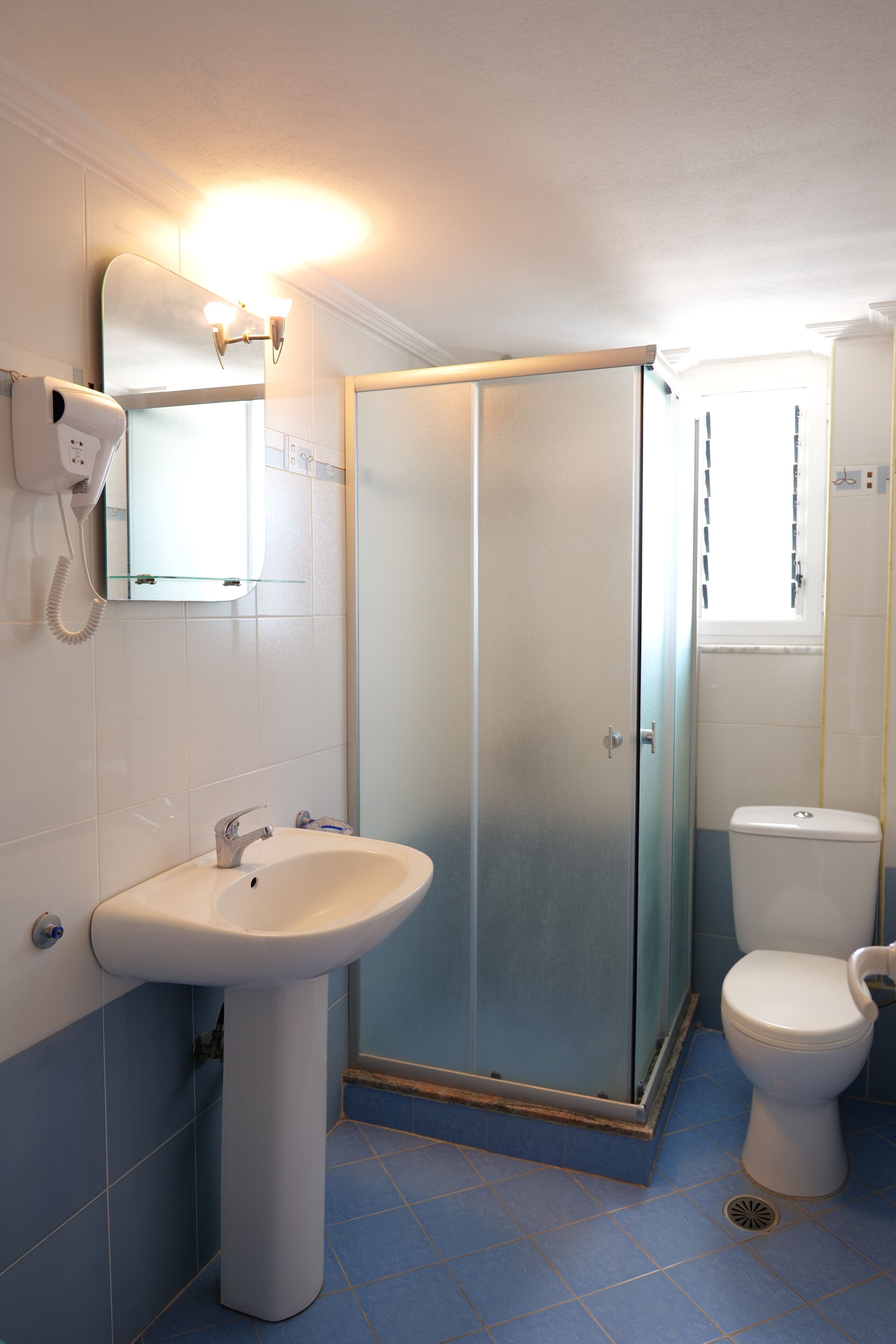 A bathroom with a sink, toilet, and a glass-enclosed shower.