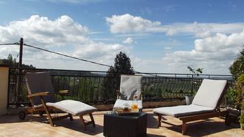 A terrace with two lounge chairs and a small table, featuring a clear view of the countryside.