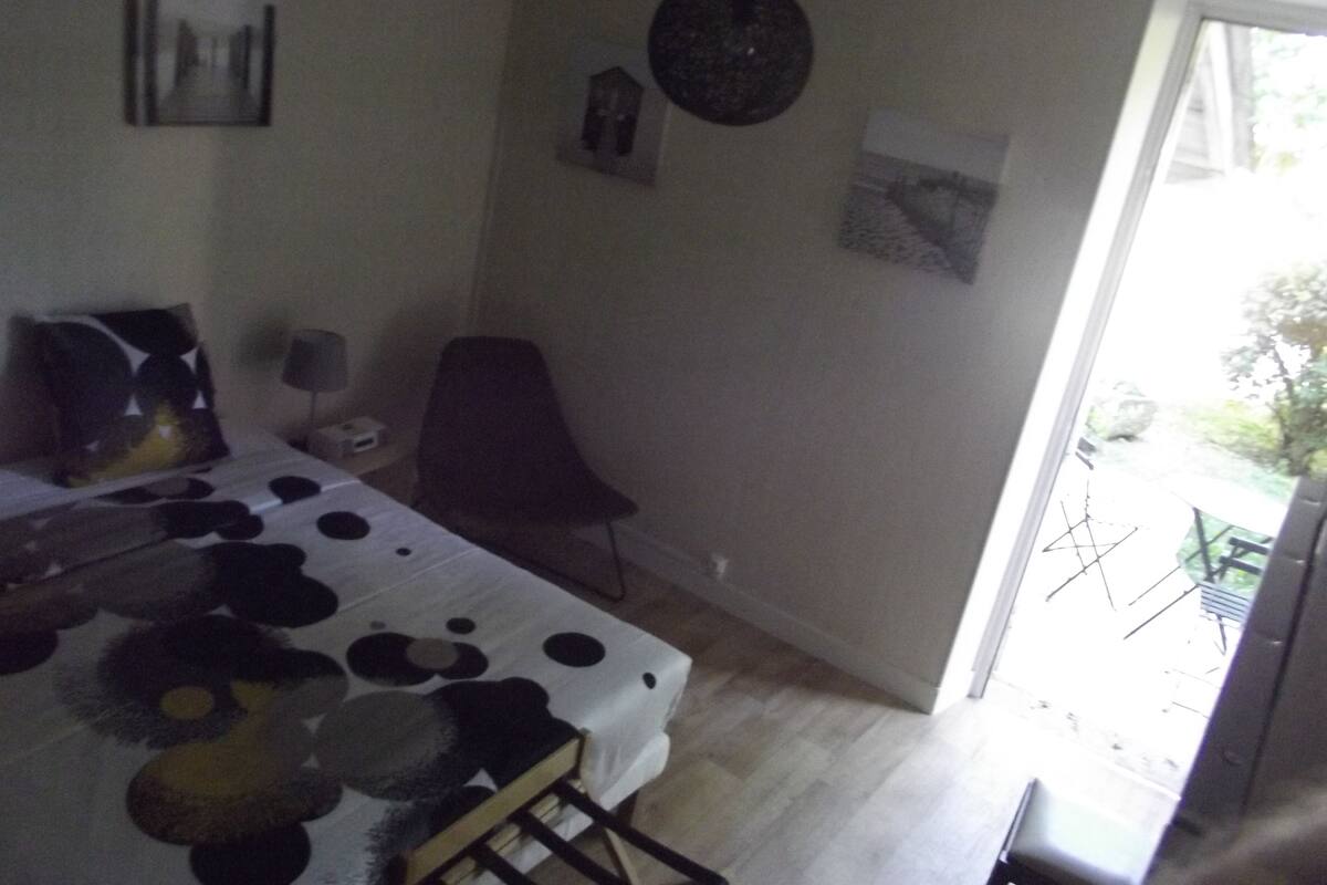 A bedroom with a bed, a chair, a desk, and a window.