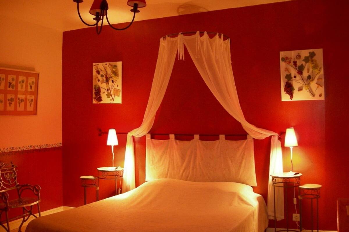 A bedroom with a bed, two bedside tables, a chandelier, and wall art.
