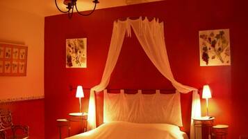 A bedroom with a bed, two bedside tables, a chandelier, and wall art.