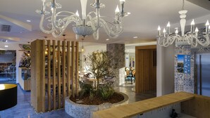 A modern interior with a wooden reception desk, a decorative plant, and a chandelier. - Boutique Hotel Serra D’Aire (Ourem)