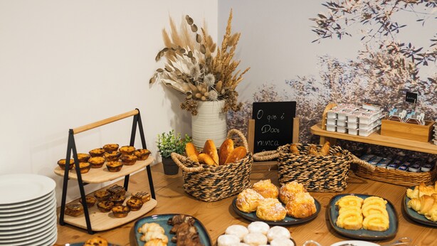 A buffet table with various pastries and breads, including croissants, muffins, and rolls. There are baskets and plates for serving, and a sign indicating the food is gluten-free. - Boutique Hotel Serra D’Aire (Ourem)