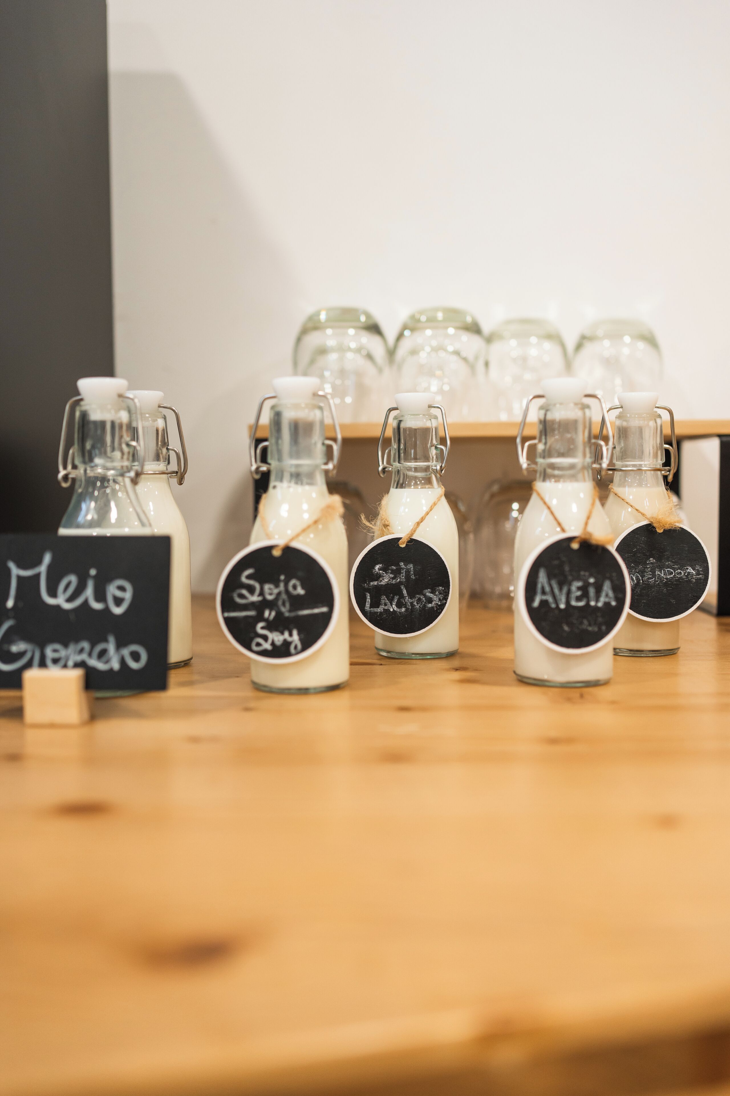 Cuatro botellas de vidrio con etiquetas sobre una superficie de madera, cada una con un nombre diferente.