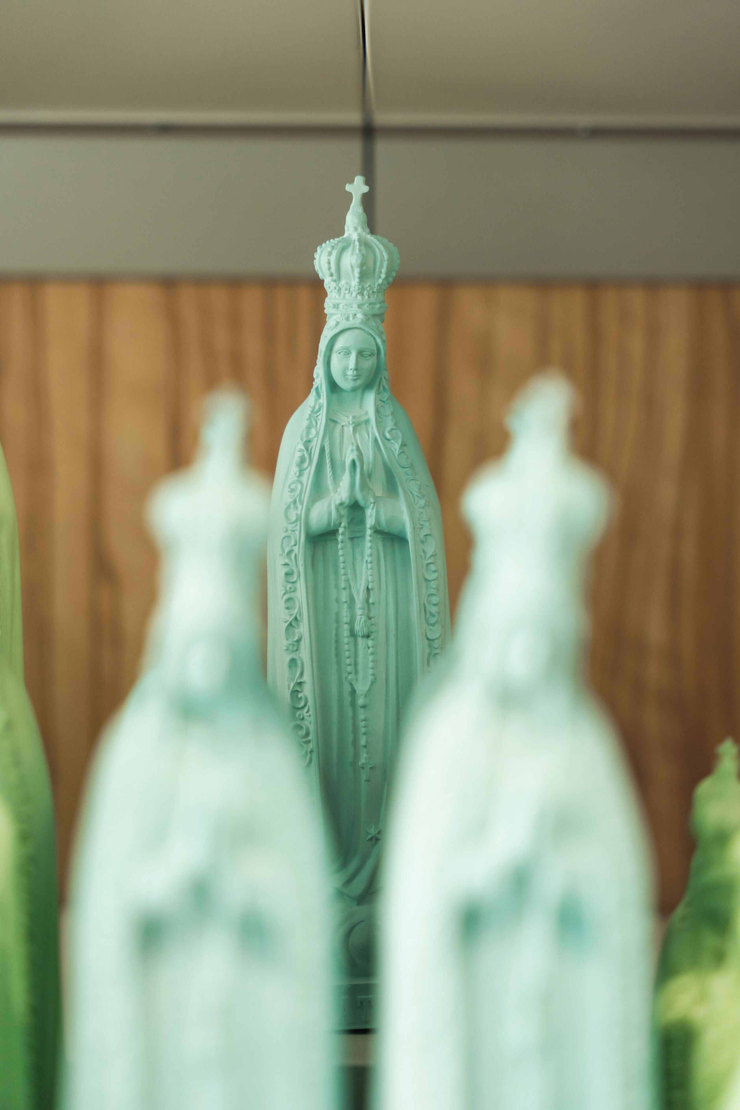 Una estatua de una figura vestida con túnica y corona, rodeada de figuras borrosas.