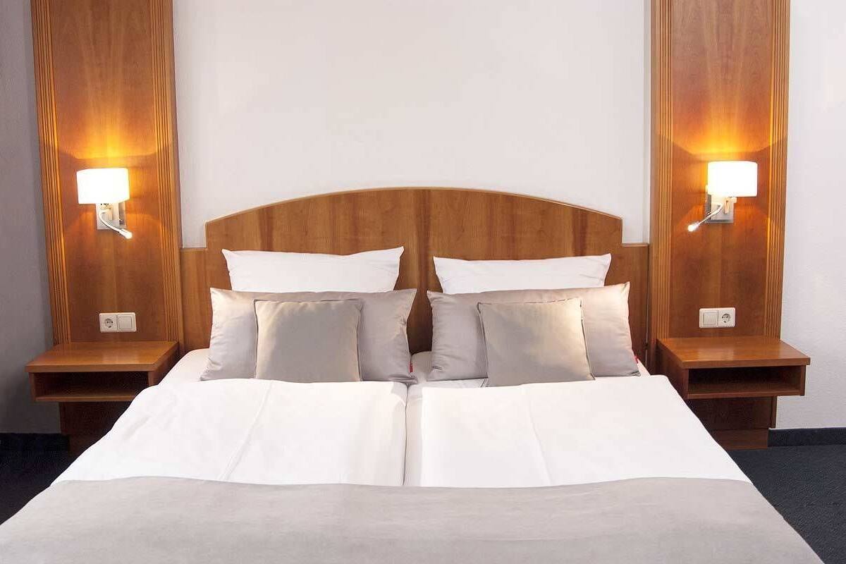 A hotel room with a large bed, two bedside tables, and wall-mounted lamps.