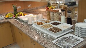 A buffet setup with various food items and utensils. - Hotel Germania (Reutlingen)