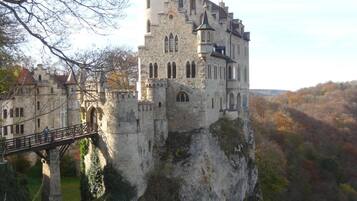 Un château perché au sommet d’une falaise, auquel on accède par un pont.