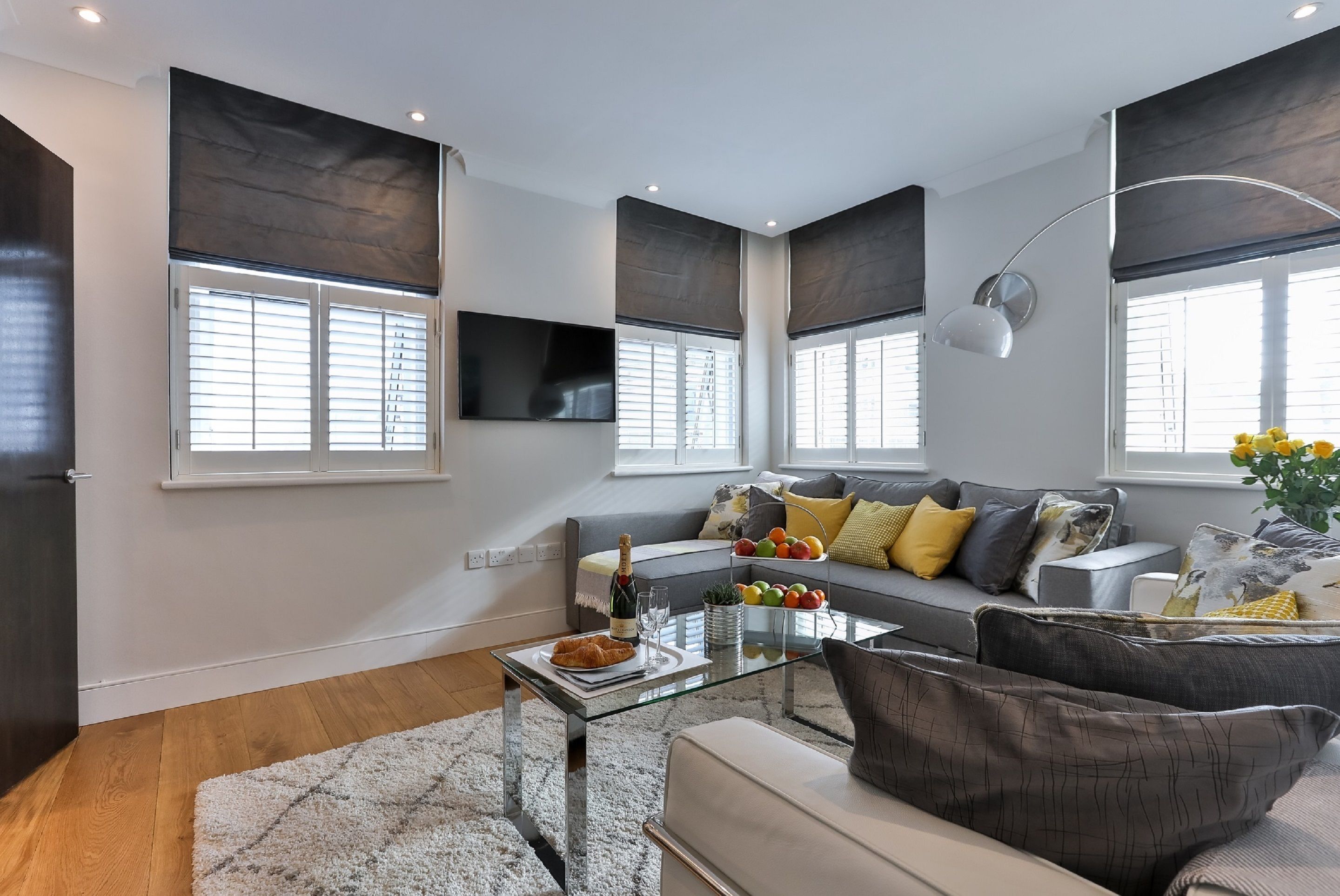 A modern living room with a sofa, coffee table, and large windows with blinds.