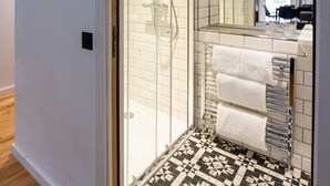 A modern bathroom with a glass shower enclosure, a tiled floor, and a visible towel rack. - Linton Collection - Blackfriars Lofts (Edinburgh)