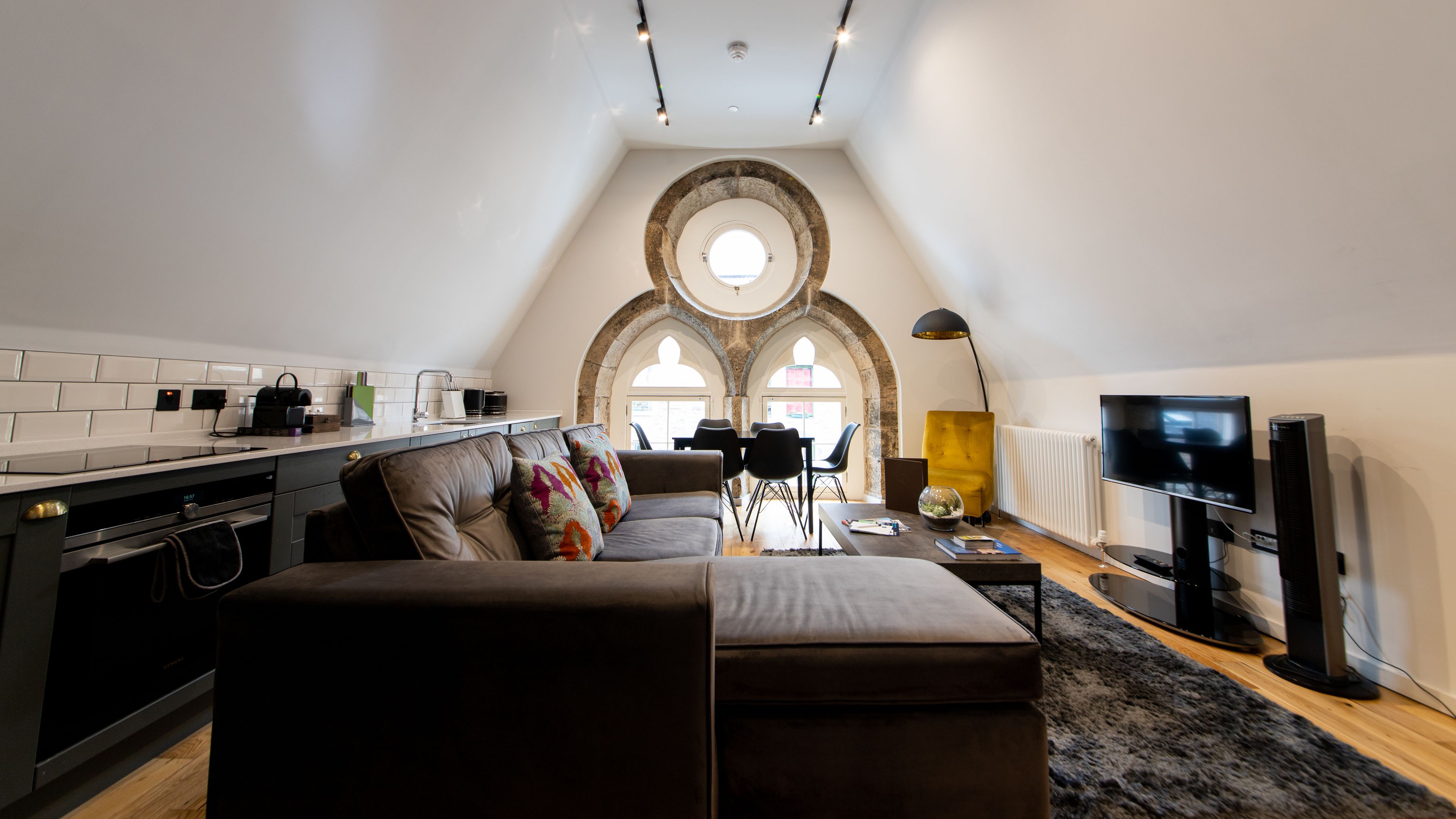 Un loft modern amb cuina, zona de menjador i espai de sala d'estar. Destaca per un sostre volta, arcs de maó descoberts i una finestra gran que aporta llum natural.
