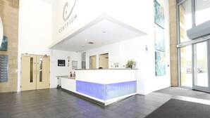 A modern reception area with a central desk, a large window, and a door to the left. - SFA New Central Woking (Woking)