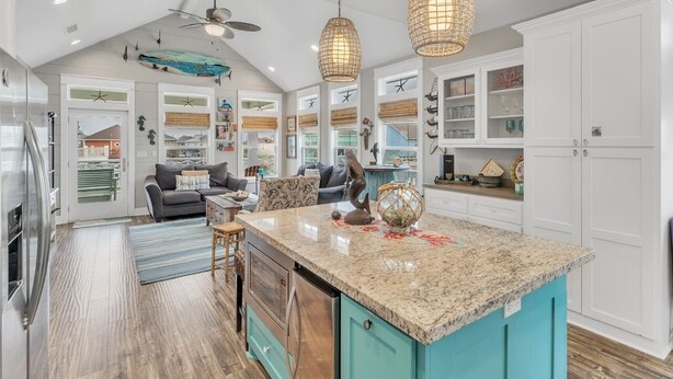 A spacious kitchen with a large island, white cabinetry, and pendant lighting.