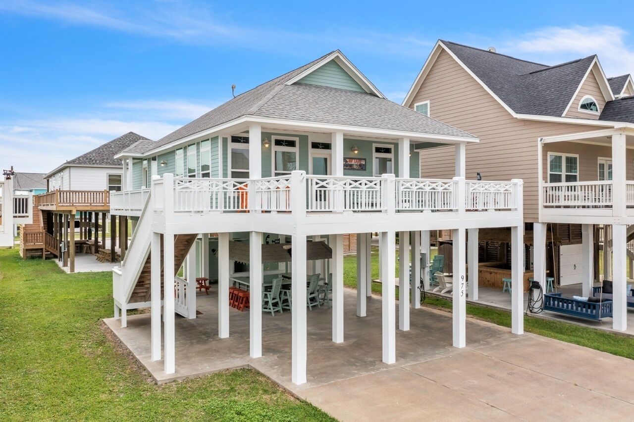 A residential property with a covered patio area, a staircase leading to a deck, and a view of neighboring houses.