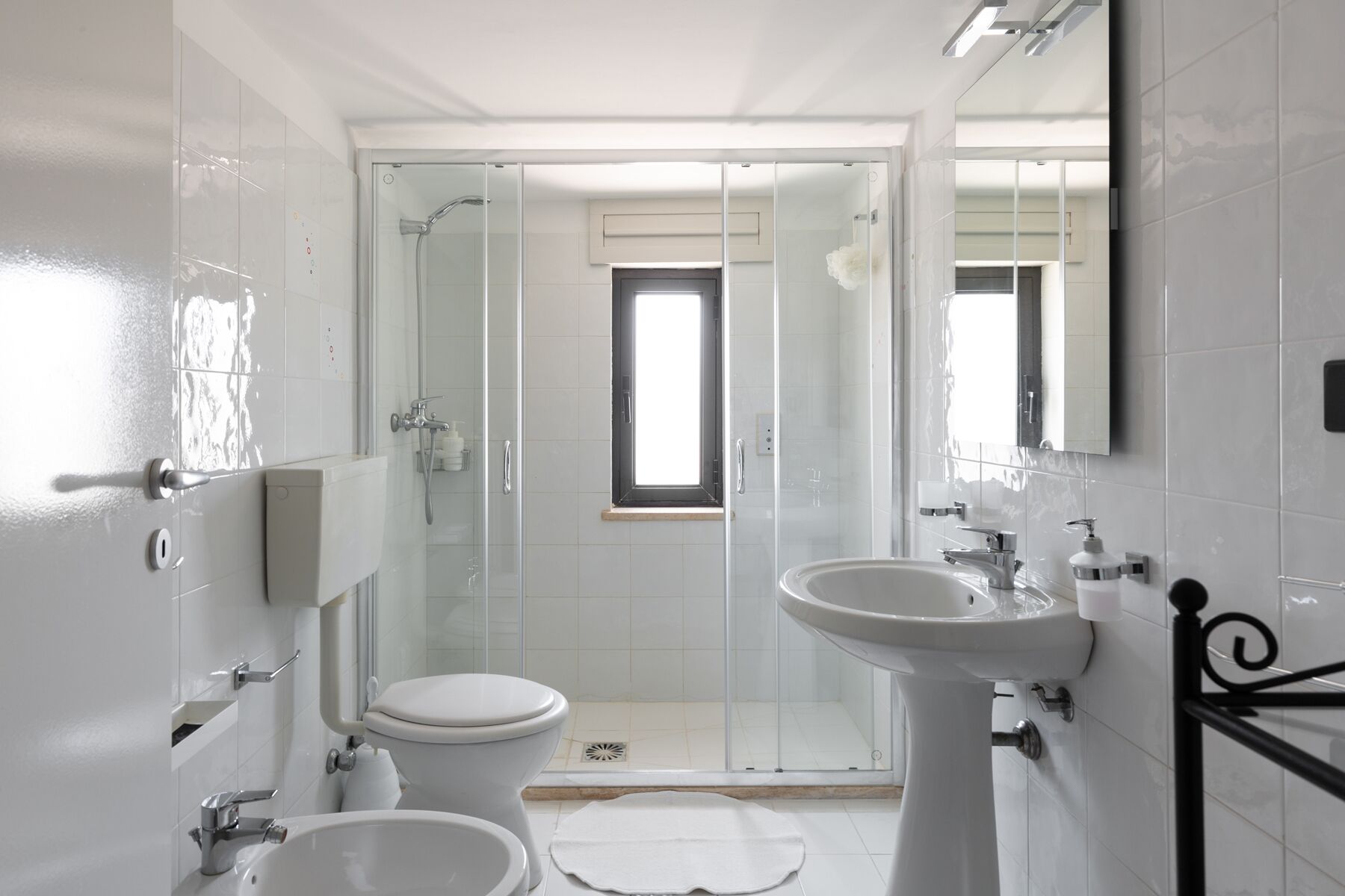 A modern bathroom with a toilet, bidet, and glass-enclosed shower.