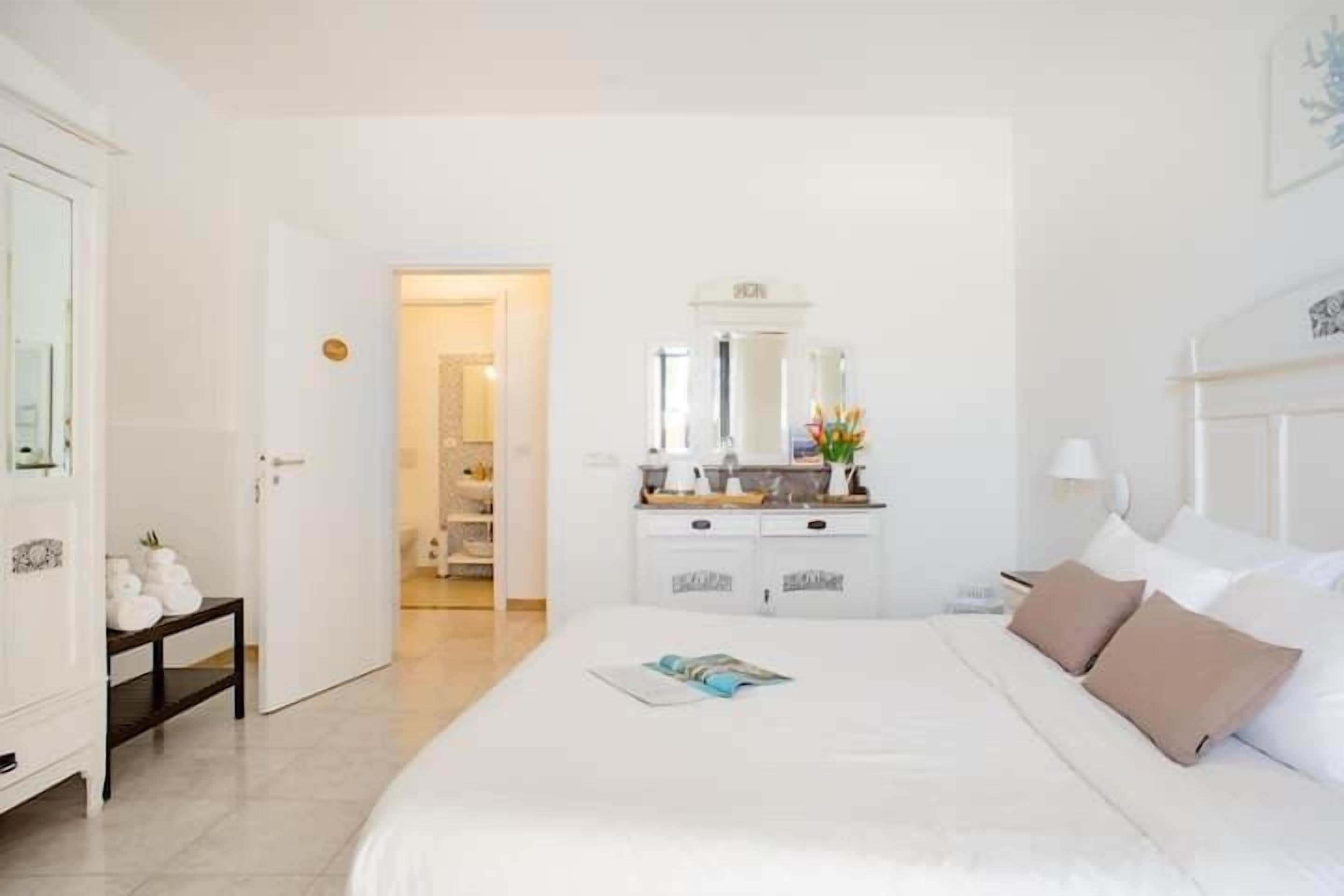 Une chambre d’hôtel comprenant un lit, une table de chevet, une commode et un miroir.