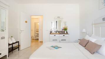 Una habitación de hotel con una cama, una mesita de noche, un tocador y un espejo.