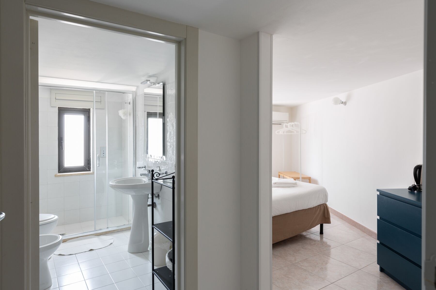 Ein modernes Badezimmer mit Duschkabine aus Glas, einem Waschbecken auf Säule und einer Toilette.