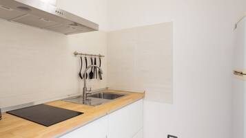 A modern kitchen with a wooden countertop, stainless steel sink, and white cabinetry.