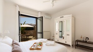 A hotel room with a bed, a wardrobe, a tray with toiletries, and a view of the outside. - Biancaleuca Rooms & Suite (Castrignano del Capo)
