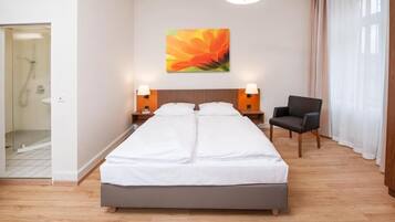A hotel room with a double bed, two bedside lamps, a chair, and a large window with curtains.