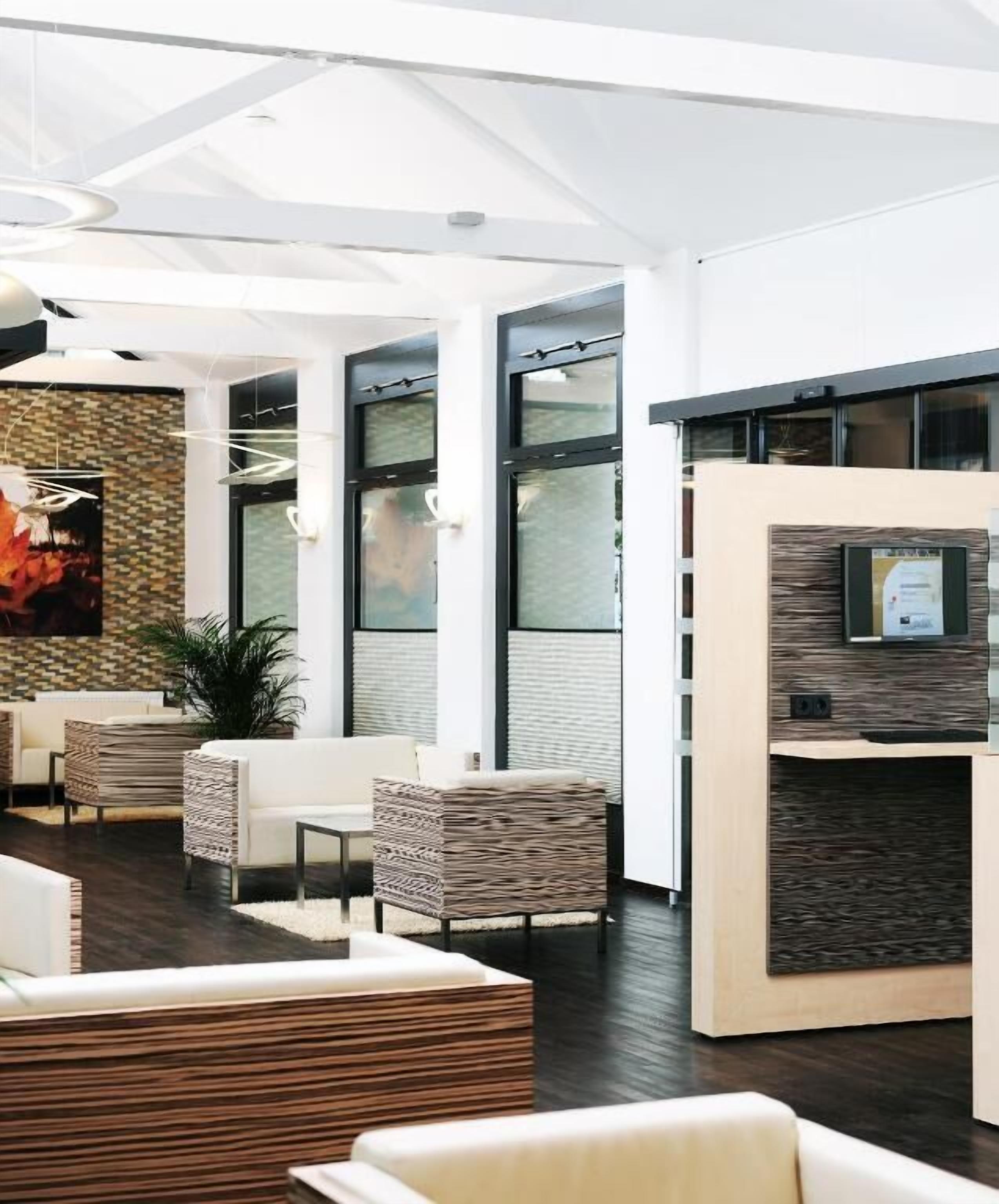A modern lobby with seating, a reception desk, and large windows.