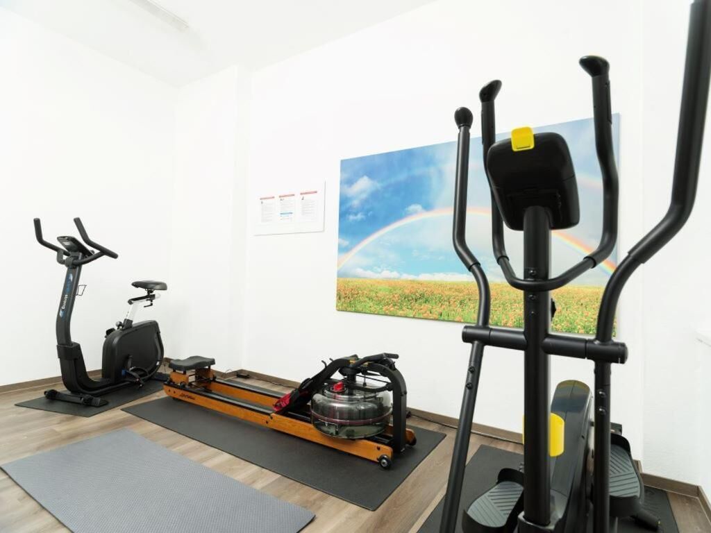 Een kamer met een hometrainer, elliptische machine en een roeimachine.