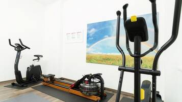Een kamer met een hometrainer, elliptische machine en een roeimachine.