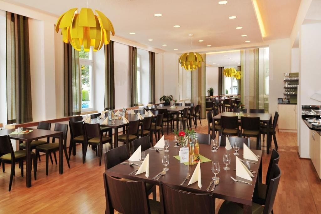 Un restaurante con varias mesas, sillas e iluminación colgante amarilla.