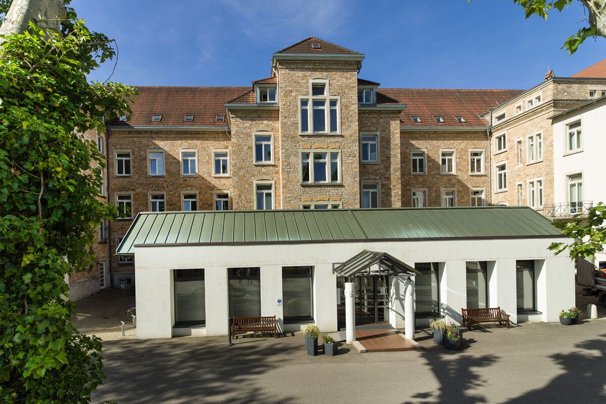 A building with a central tower, multiple windows, and a green roof.