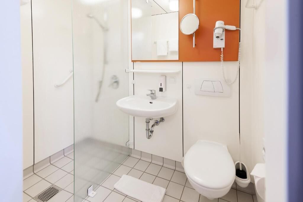 Un baño moderno con cabina de ducha de vidrio, un lavabo blanco y un inodoro.