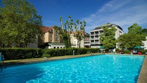 Una piscina rodeada de edificios bajo un cielo azul despejado.