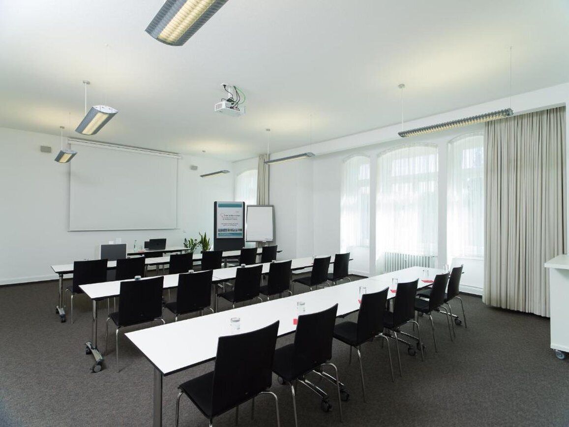 A conference room with a long table, black chairs, a whiteboard, and a projector.