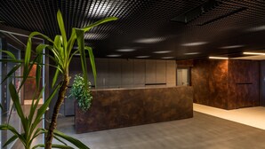 A modern interior with a reception desk, a large plant, and a metallic ceiling. - GA Luxury Apartments Wawrzynca 21 (Kraków)