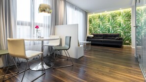A modern living room with a dark sofa, a round table with chairs, and a decorative vase with flowers. - GA Luxury Apartments Wawrzynca 21 (Kraków)