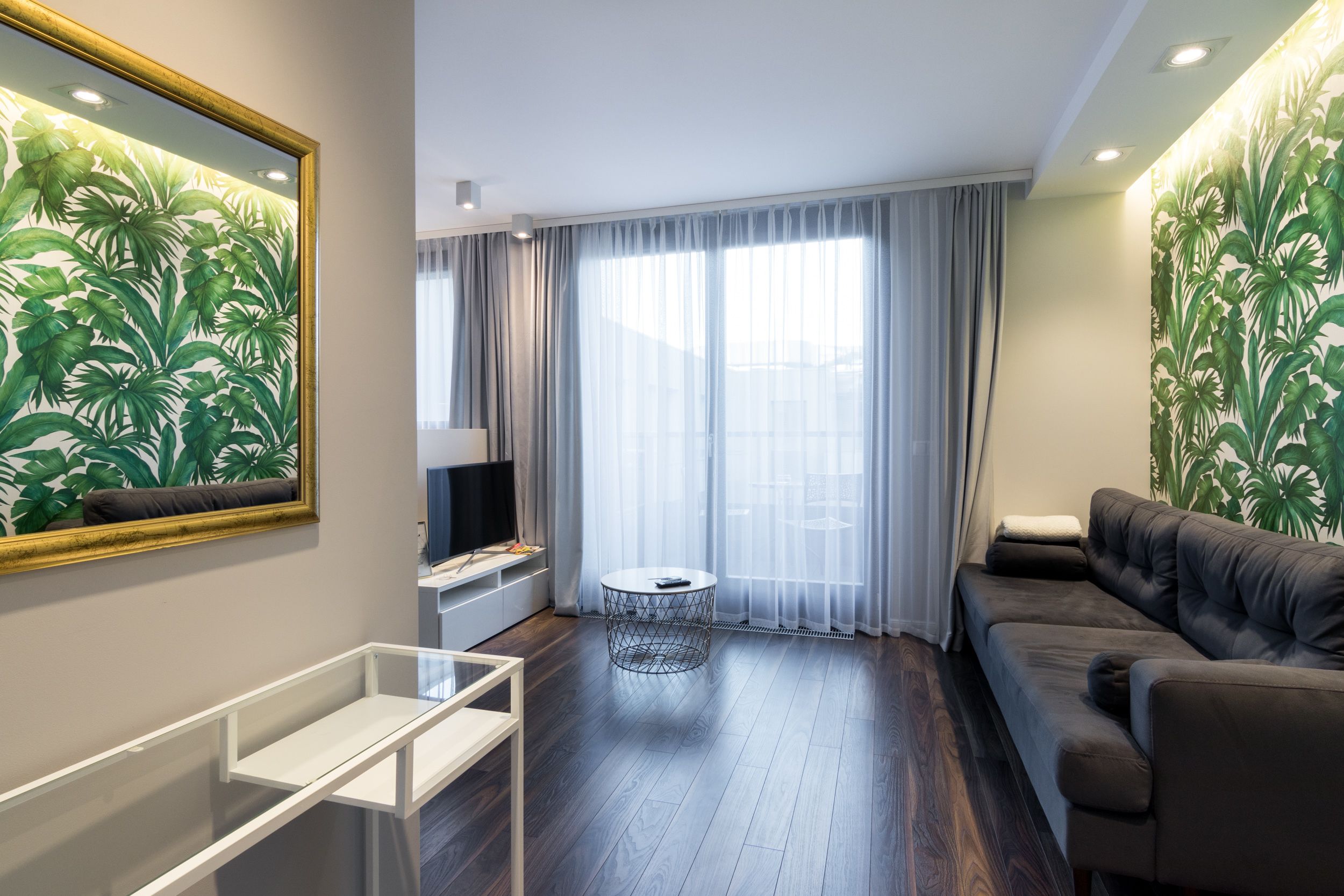 Un salon moderne avec un canapé, une table basse et un téléviseur.
