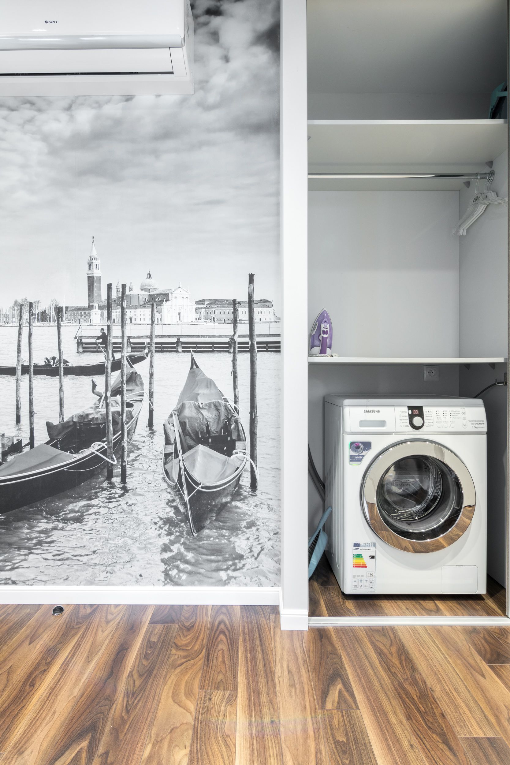 A laundry room with a Samsung washing machine and a black and white photo of Venice's Grand Canal.