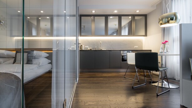 A modern hotel room with a glass partition separating the bedroom from the kitchenette. - GA Luxury Apartments Wawrzynca 21 (Kraków)