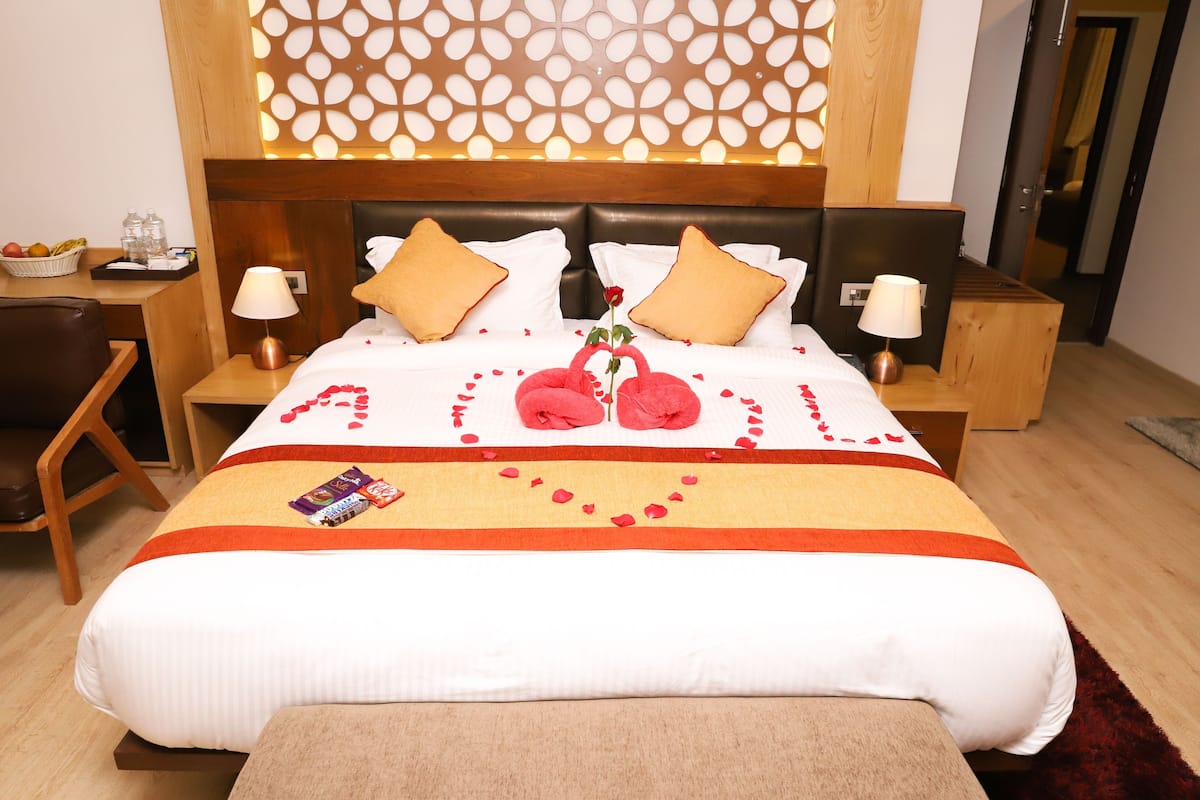 A hotel room with a large bed, two nightstands, a wooden headboard, and a decorative wall panel.