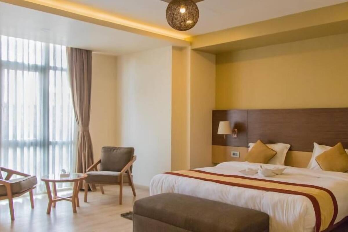 A hotel room with a large bed, a desk, a chair, and a sofa.