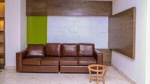 A modern living room with a brown leather sofa, a wooden side table, and a geometric-patterned wall. - Retro Hotel and Spa (Kathmandu)